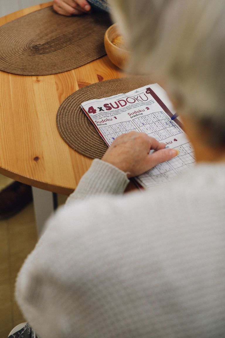Pessoa resolvendo um desafio de Sudoku em uma mesa de madeira.